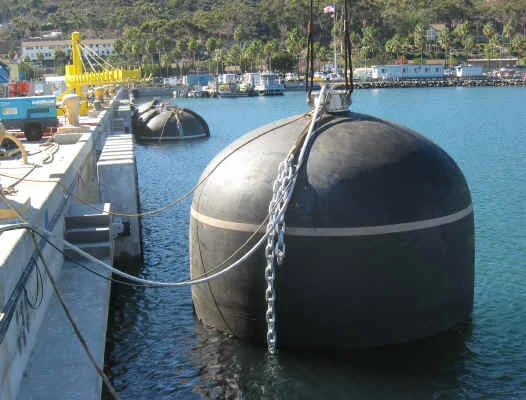 Hydro-pneumatic submarine fender installed vertically at a berth, water-ballasted to hold contact below the waterline