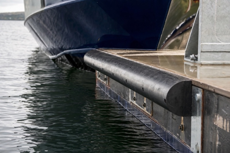 D-section rubber fenders bolted along a pontoon edge with a vessel alongside