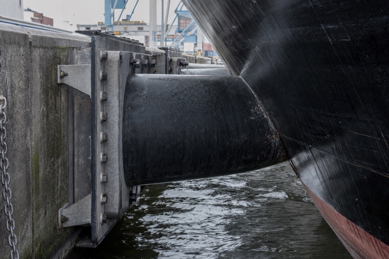 Super cone rubber fender with a steel front panel bolted to a quay wall with a ship alongside